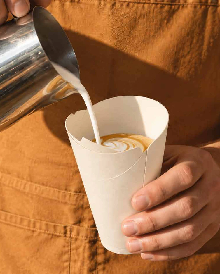 Barista sirviendo un latte en un vaso re:set